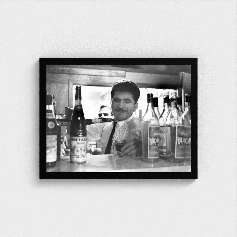 Pouring a Glass Behind the Counter — 12 × 16 inch black framed print