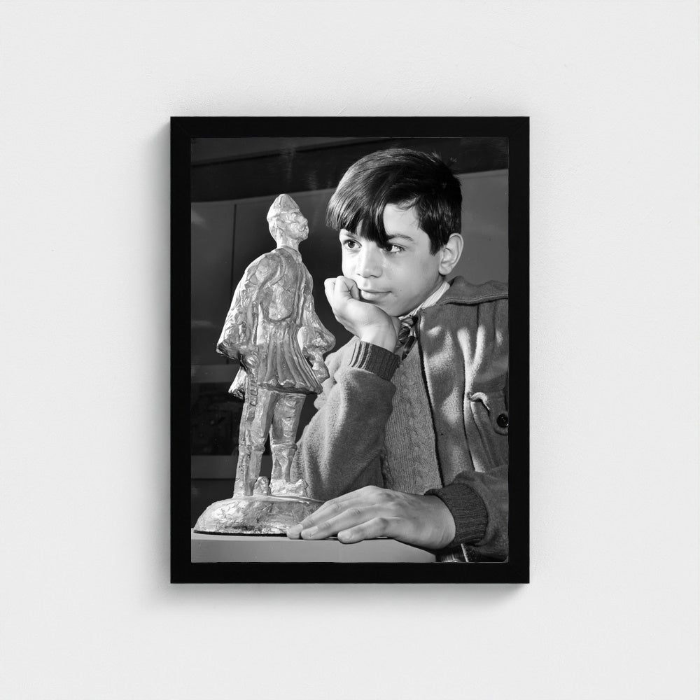 A Child with an Evzone Statuette — 12 × 16 inch black framed print