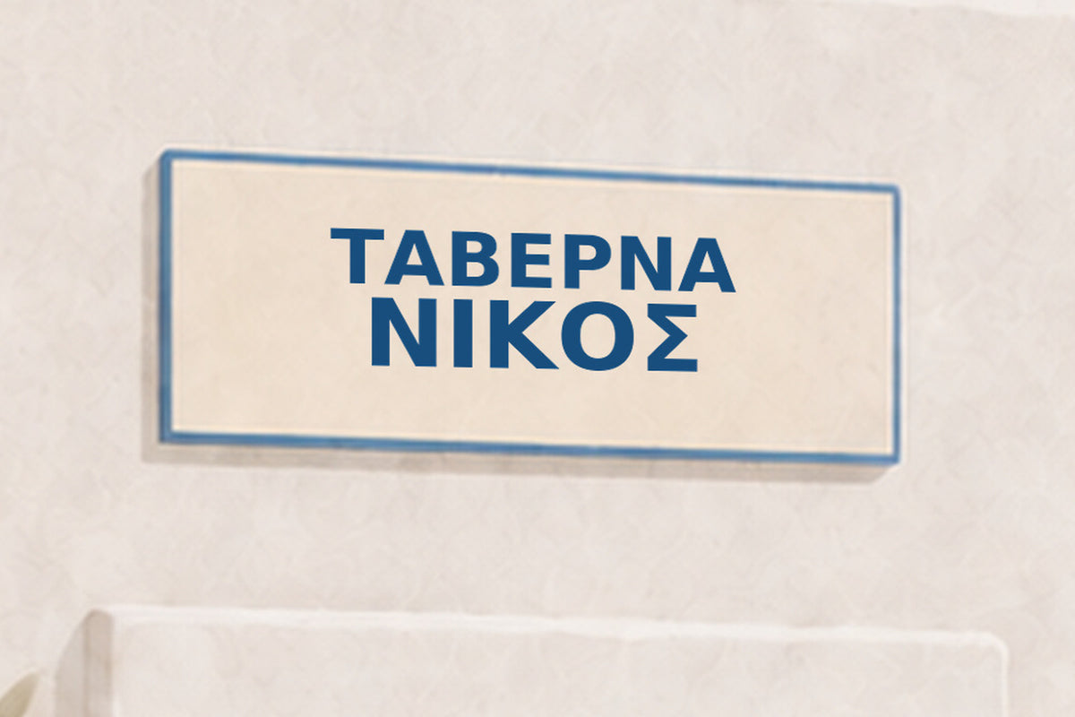 Aegean Modernist ΝΙΚΟΣ — close-up of the uppercase Greek name on the taverna sign.