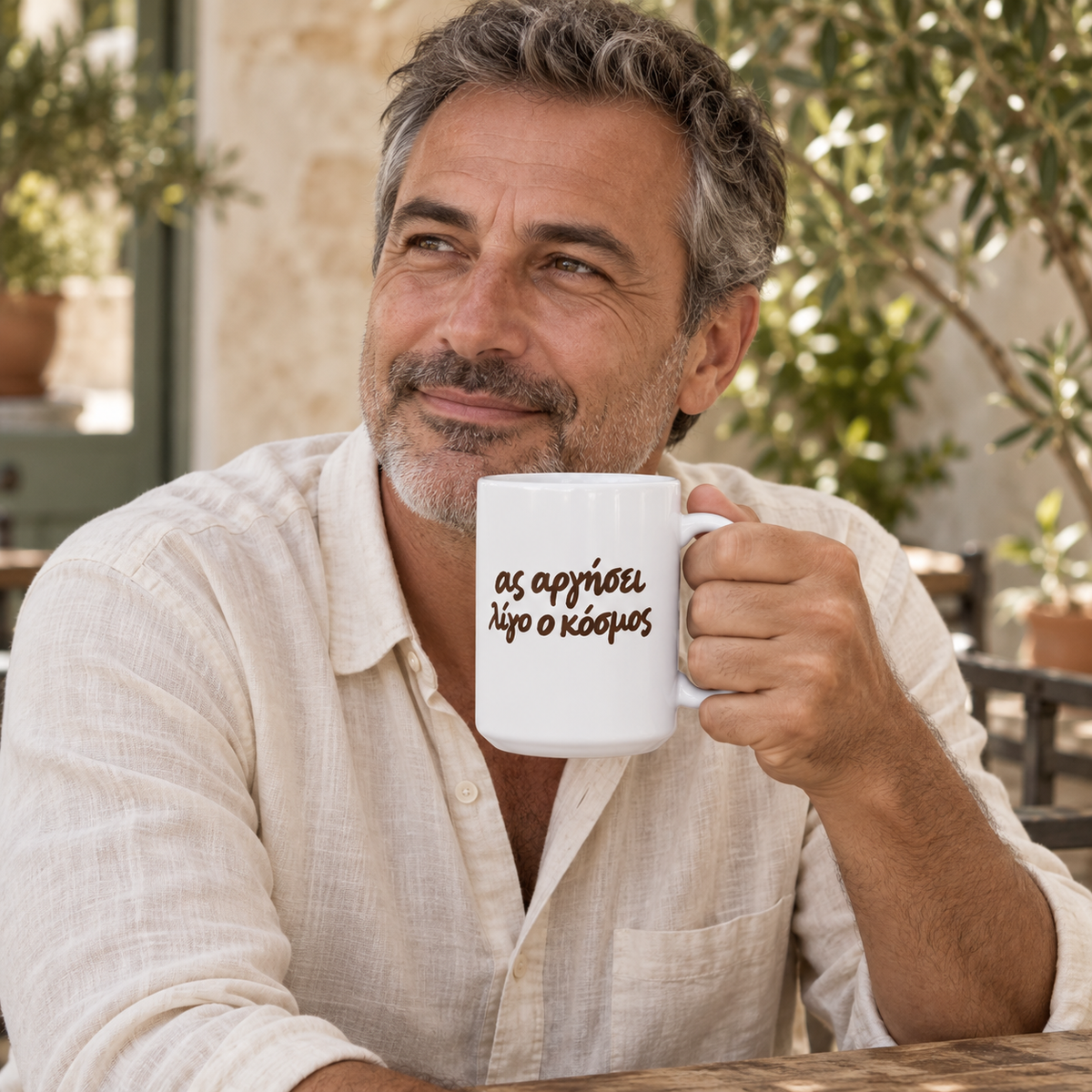 AI-generated lifestyle image: man enjoying coffee in a courtyard with the Ας Αργήσει Λίγο ο Κόσμος white 15 oz mug