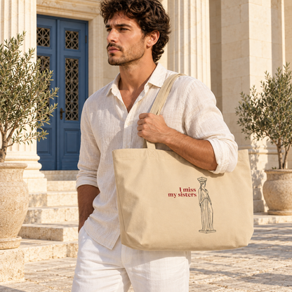 Lifestyle mockup: man carrying the Large Oyster Caryatid organic cotton tote in a sunlit Greek courtyard