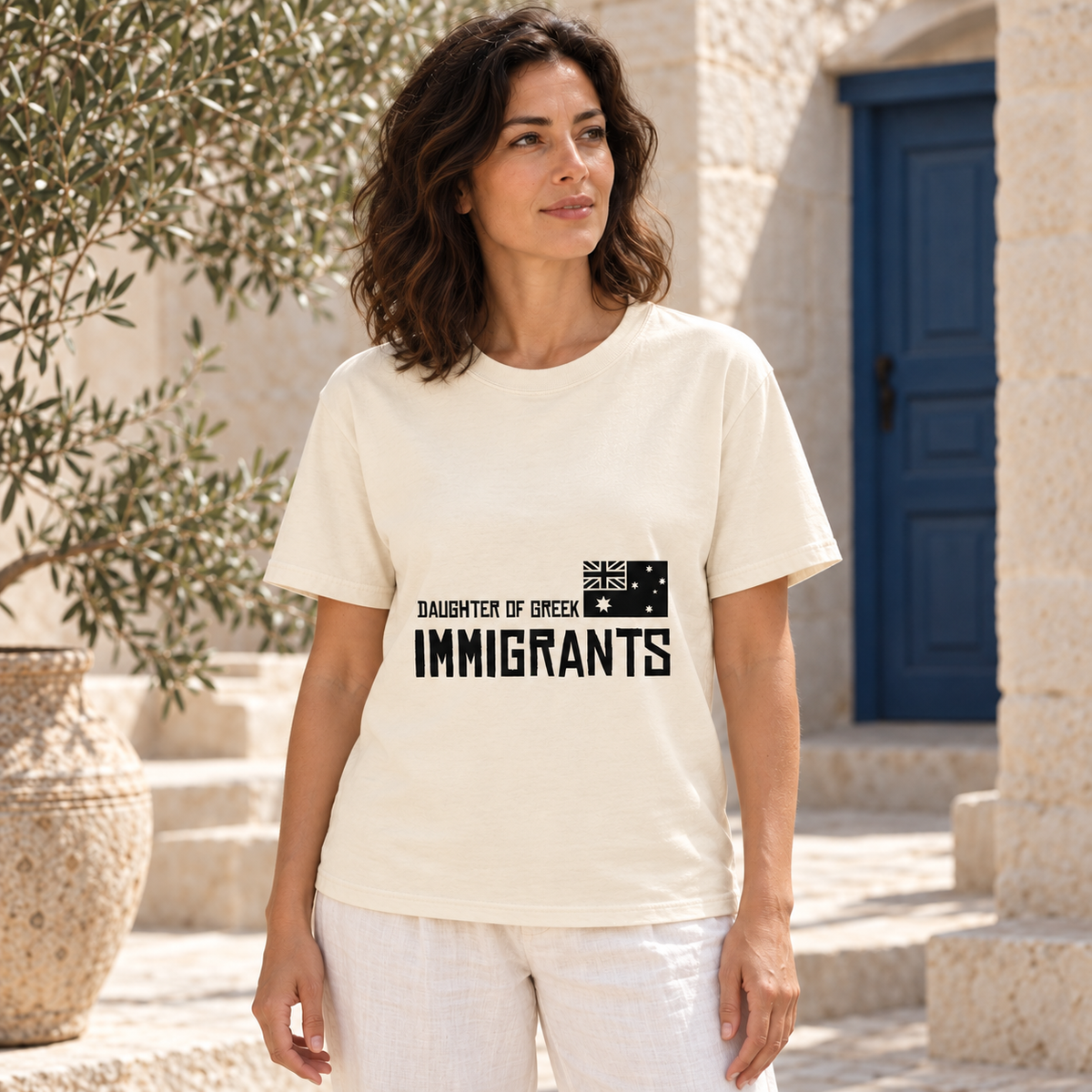 Daughter of Greek Immigrants — Australia — Ivory shirt worn by a model in a sunlit stone courtyard; AI-generated lifestyle mockup